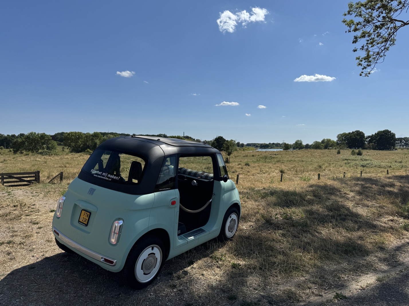 Fiat Topolino geparkeerd in het open Limburgse landschap bij Venlo met uitzicht op de Maas en kerkdorp Steyl