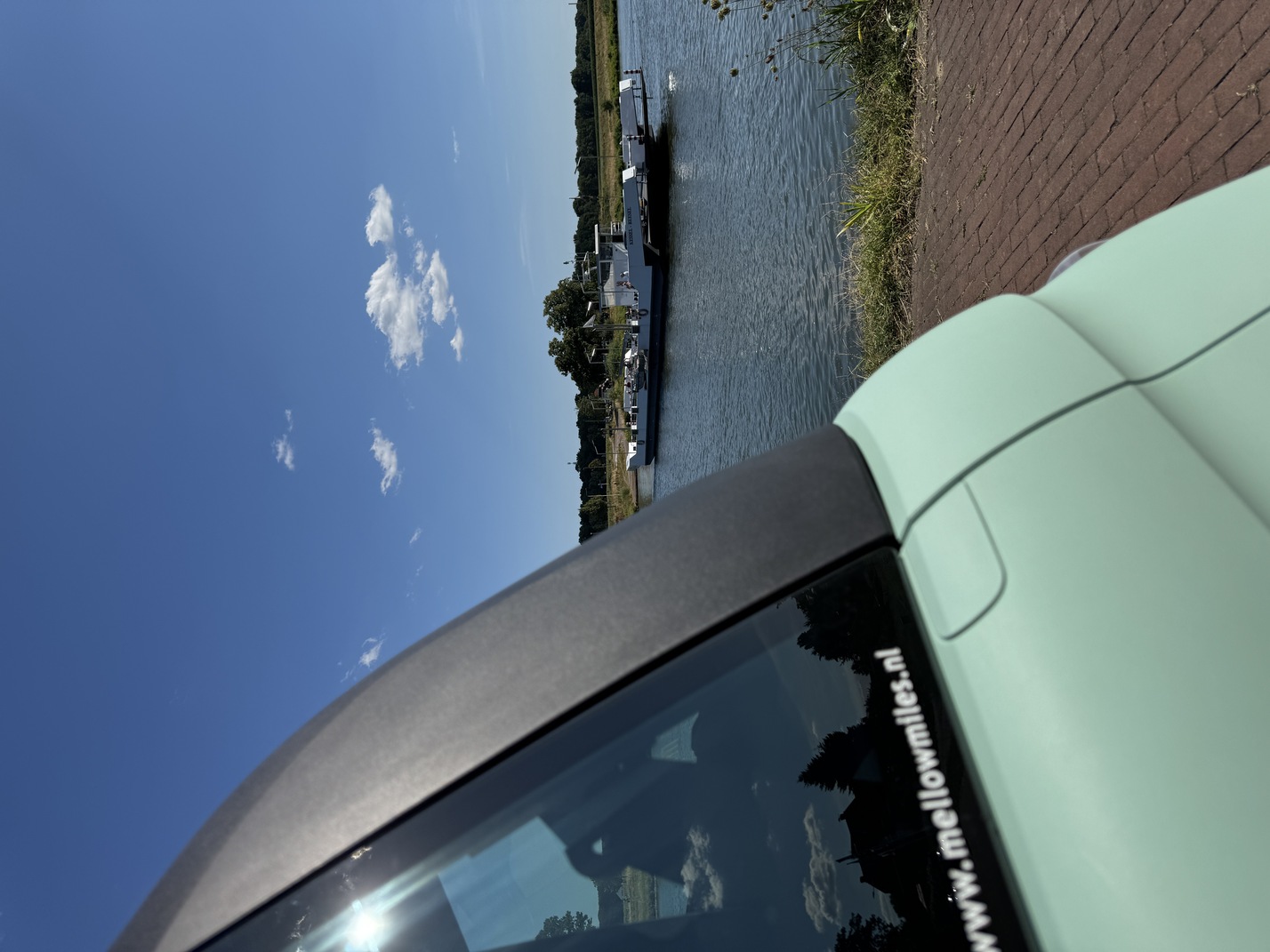 Close-up van de Fiat Topolino met uitzicht op het veerpont Kessel-Beesel over de Maas
