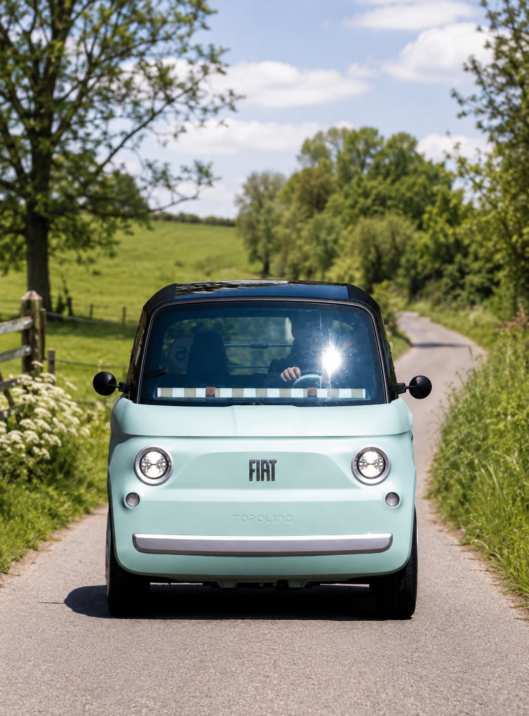 Fiat Topolino op een rustige landweg tussen groene weilanden