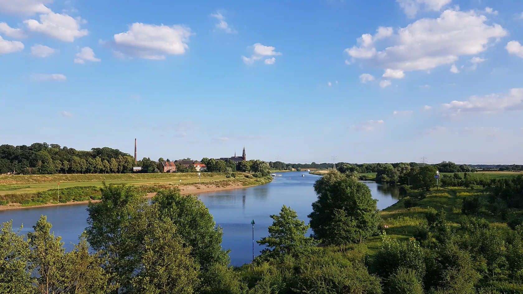 Weids uitzicht over de Maas langs de Romeinenweg met een pittoresk Limburgs dorp op de achtergrond